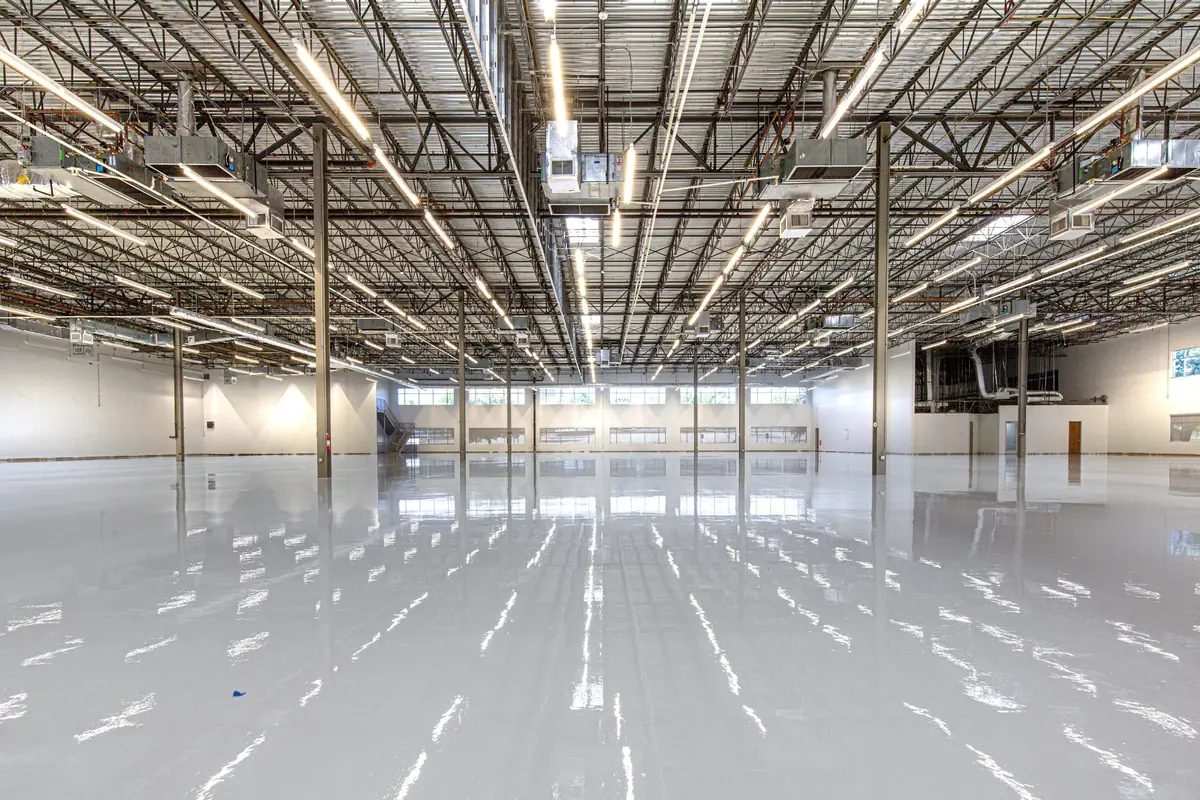 Empty industrial building with a fresh high-gloss gray epoxy floor reflecting ceiling lights