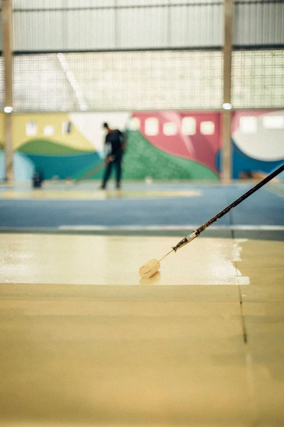 Long-handled roller spreading a fresh coat across a floor