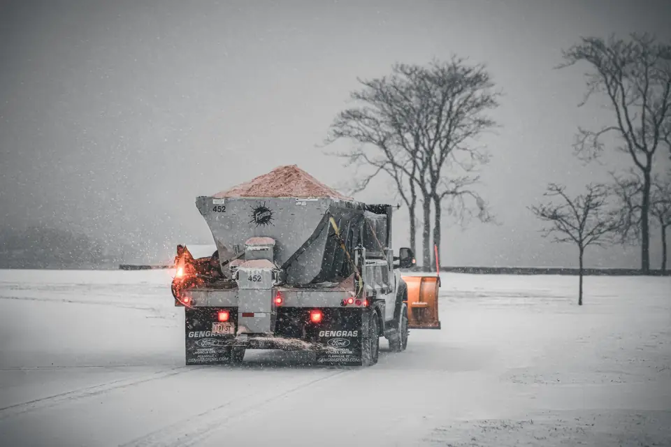 Snowplow truck spreading road salt during a winter storm